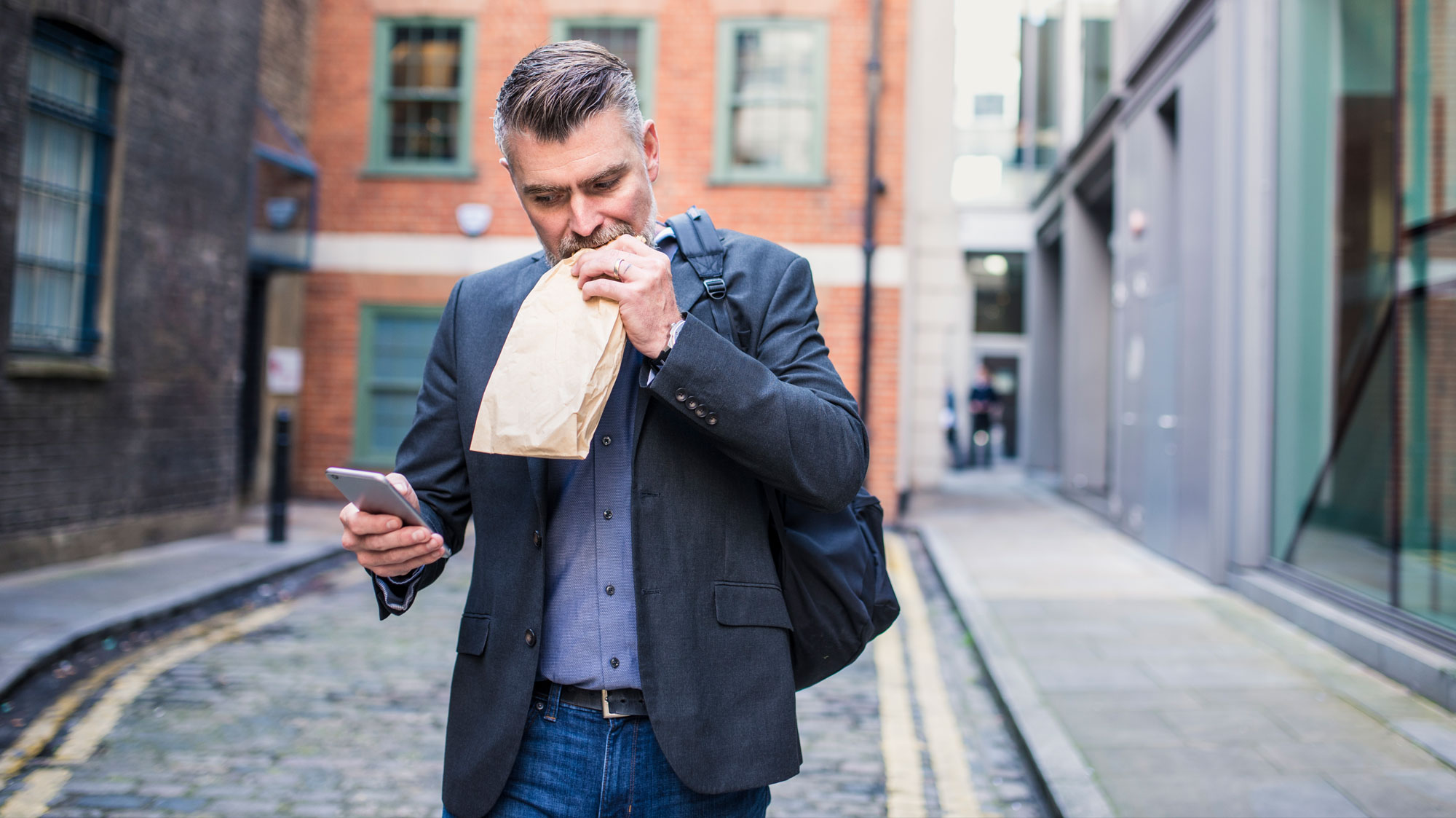 Man walking, eating and looking at his phone