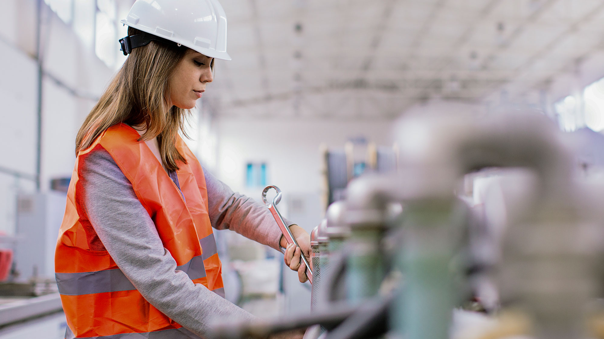 Woman in a hard hat and safety vest on a manufacturing line
